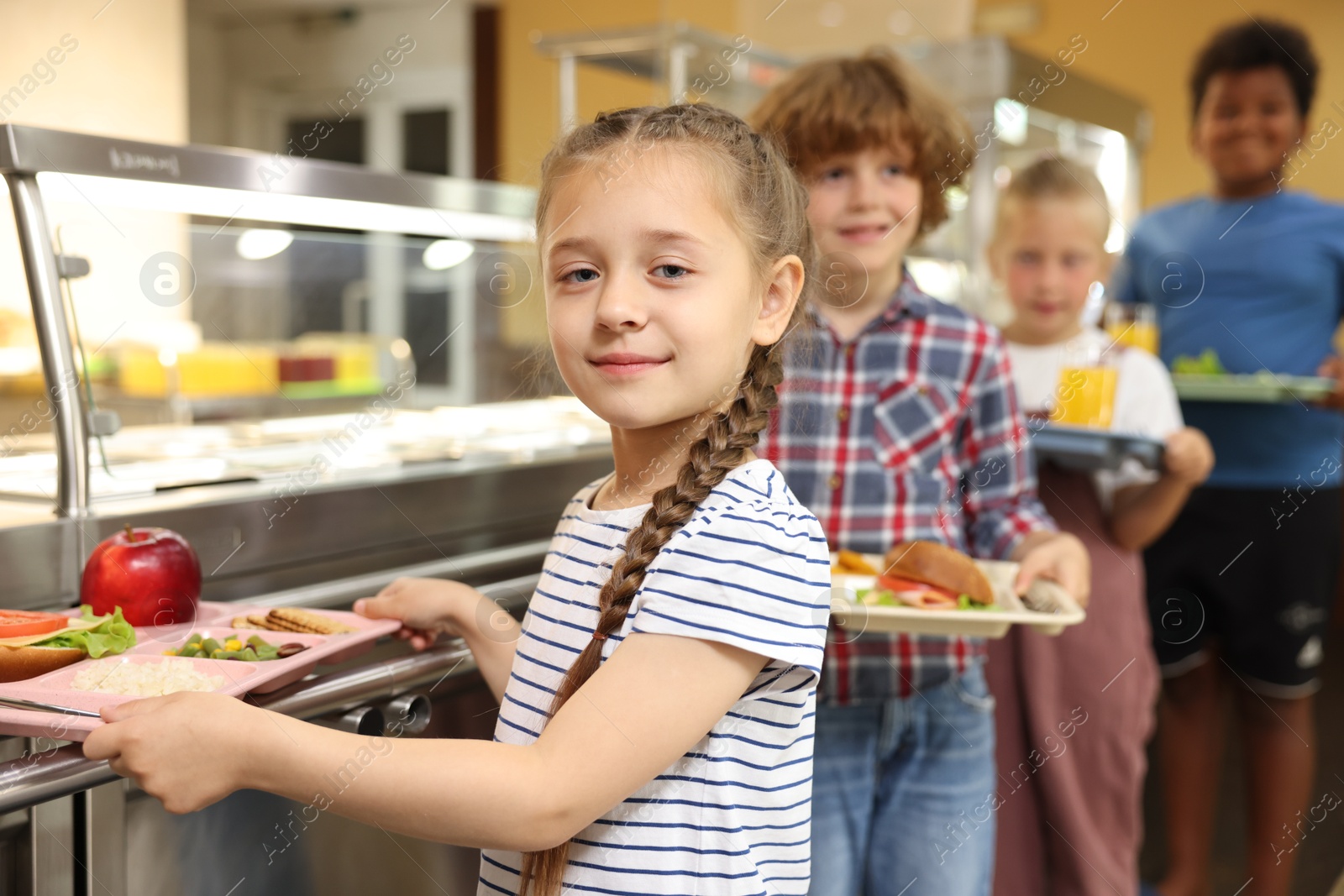 Little girl with tray of tasty food in school canteen, selective focus Photo of Little girl with tray of tasty food in school canteen, selective focus