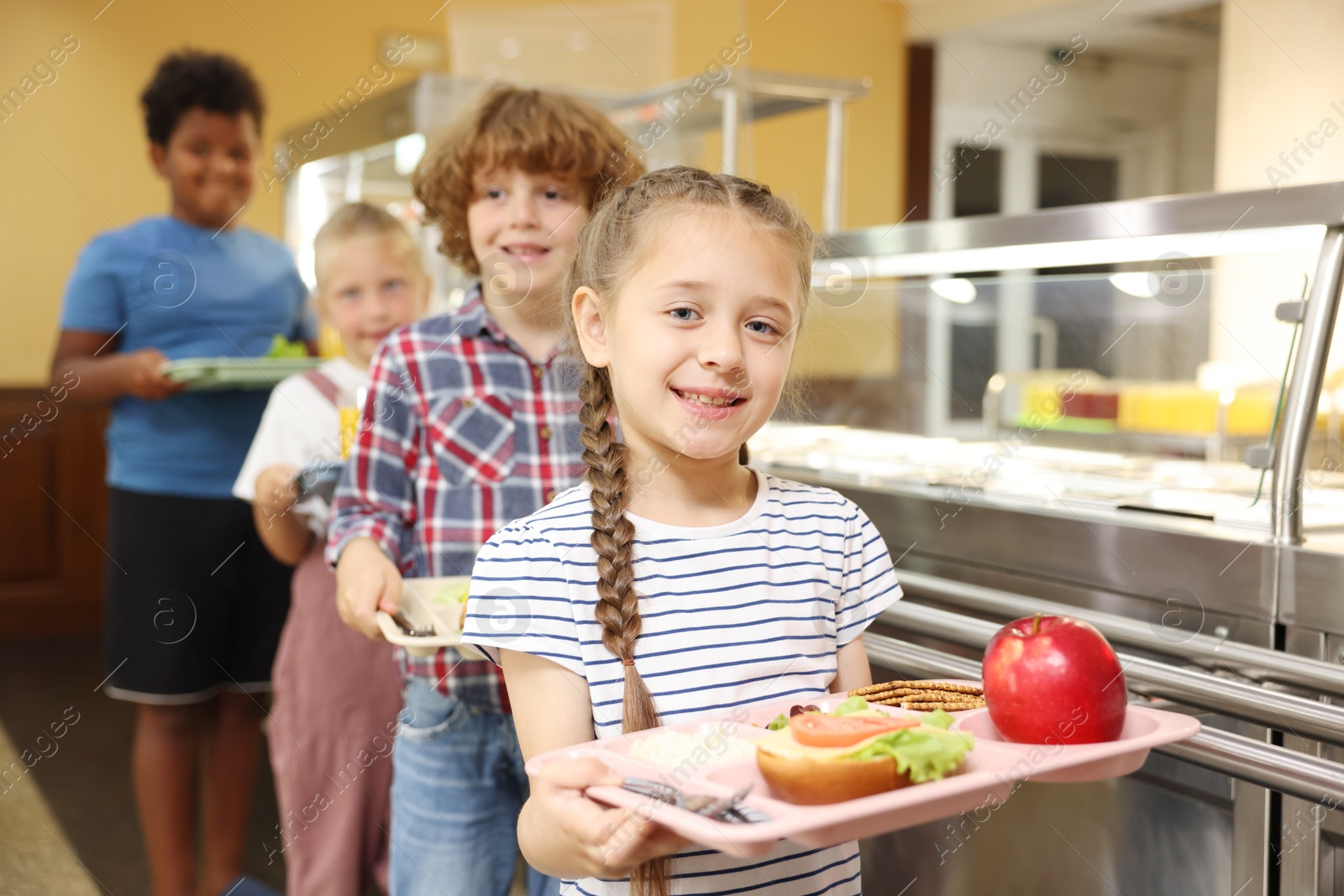 Little girl with tray of tasty food in school canteen, selective focus Photo of Little girl with tray of tasty food in school canteen, selective focus