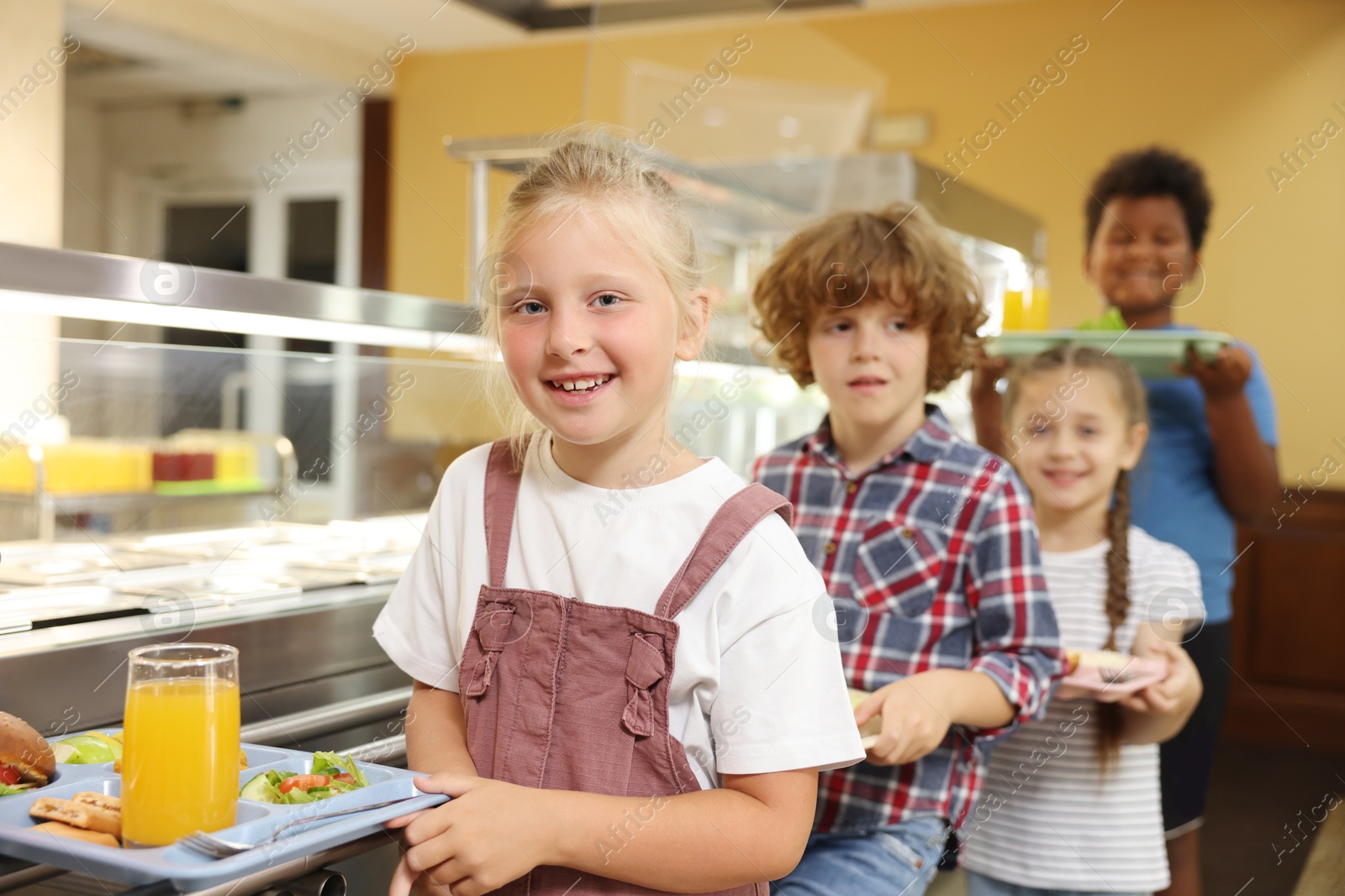 Little girl with tray of tasty food in school canteen, selective focus Photo of Little girl with tray of tasty food in school canteen, selective focus
