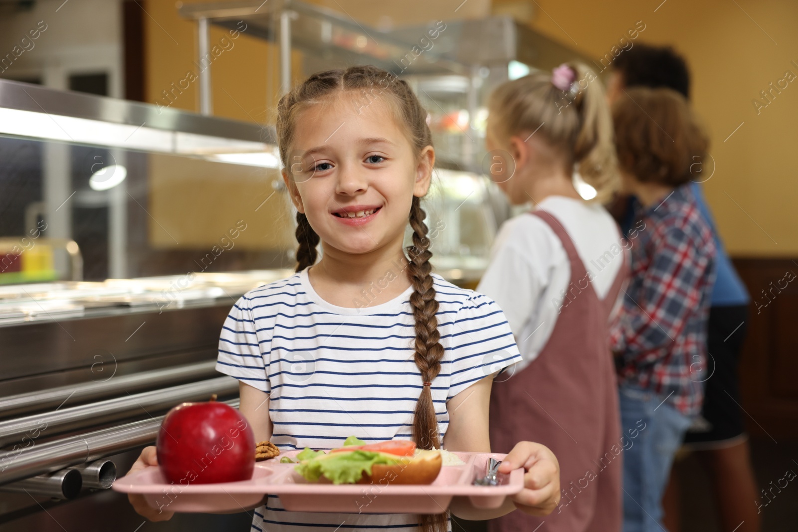 Little girl with tray of tasty food in school canteen, selective focus Photo of Little girl with tray of tasty food in school canteen, selective focus