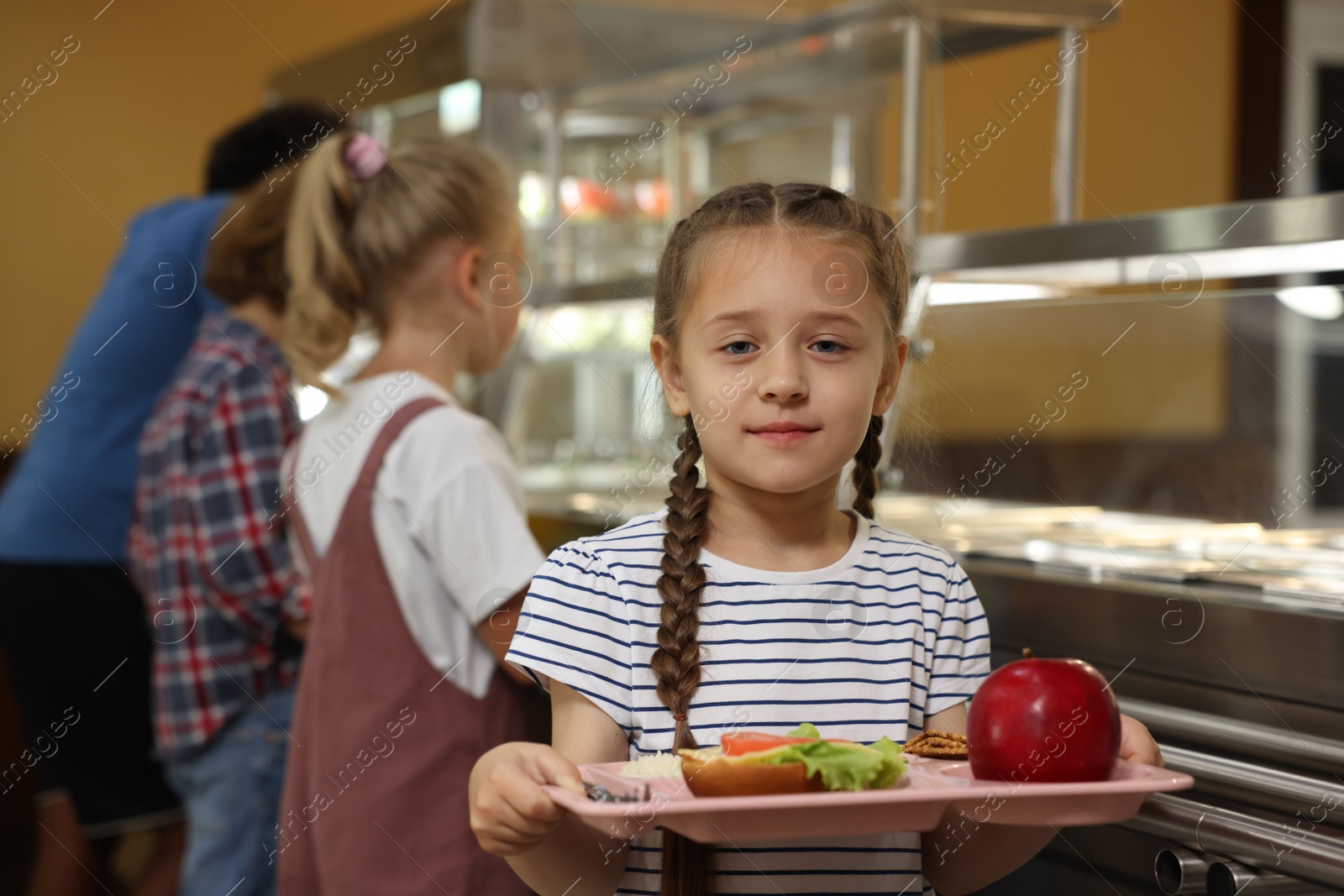 Little girl with tray of tasty food in school canteen, selective focus Photo of Little girl with tray of tasty food in school canteen, selective focus