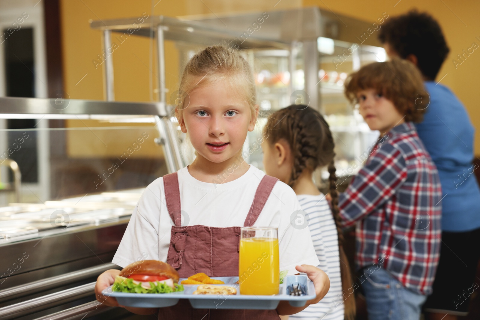Little girl with tray of tasty food in school canteen, selective focus Photo of Little girl with tray of tasty food in school canteen, selective focus