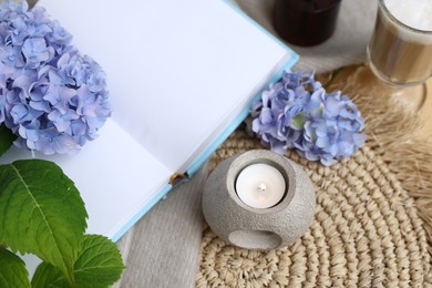 Photo of Spa composition with burning candle, book and beautiful hydrangea flowers on table, above view