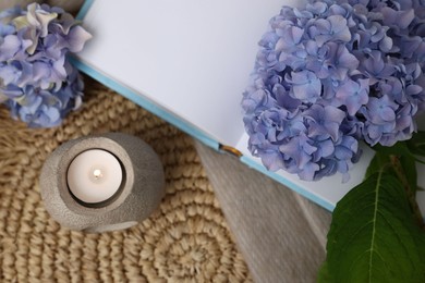 Photo of Spa composition with burning candle, book and beautiful hydrangea flowers on table, flat lay