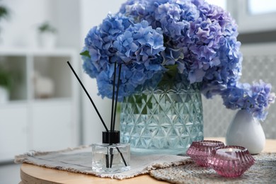 Photo of Spa composition with burning candles, reed air freshener and beautiful hydrangea flowers on table