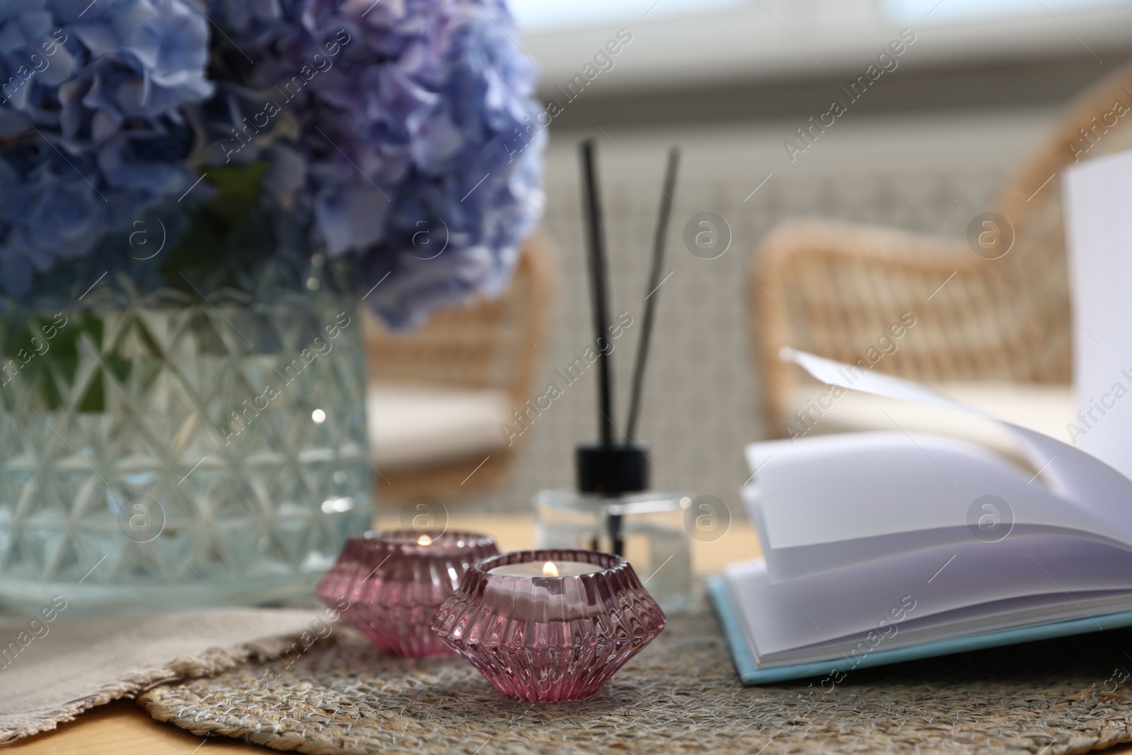 Spa composition with burning candles, reed air freshener, beautiful hydrangea flowers and book on table, selective focus Photo of Spa composition with burning candles, reed air freshener, beautiful hydrangea flowers and book on table, selective focus