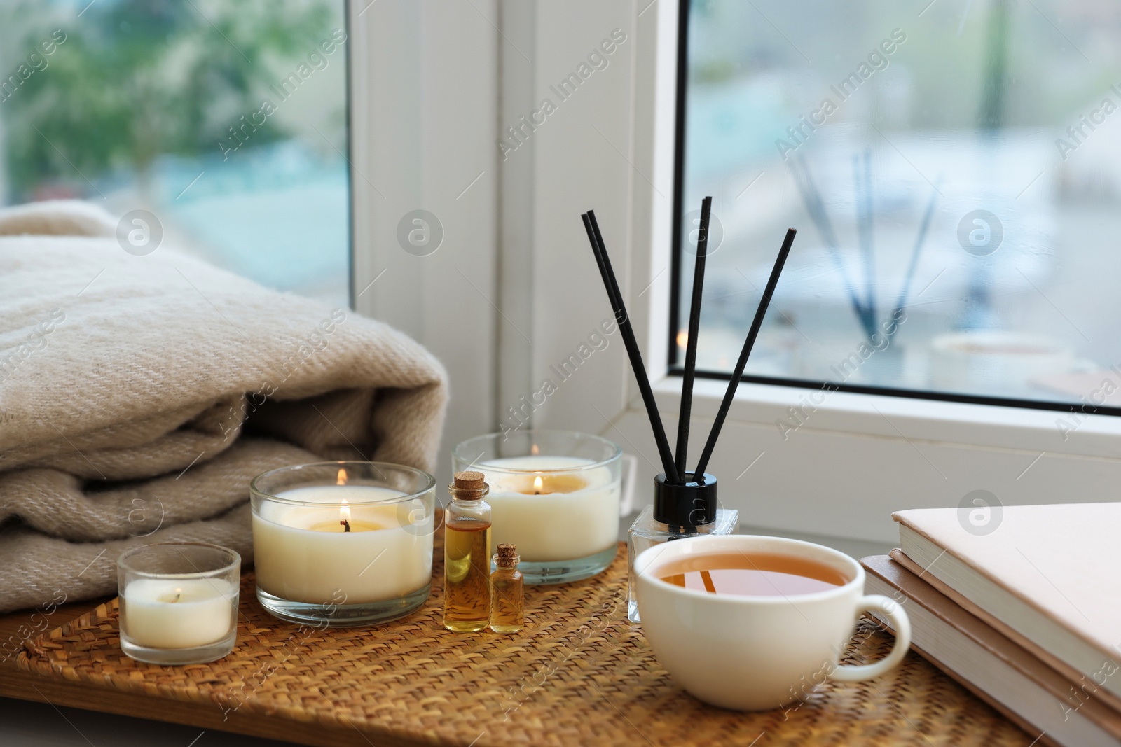 Spa composition with burning candles and reed air freshener on windowsill Photo of Spa composition with burning candles and reed air freshener on windowsill