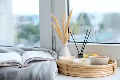 Photo of Spa composition with burning candles and reed air freshener on windowsill