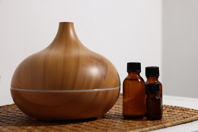 Photo of Spa composition with aroma oil diffuser and cosmetic products on table indoors, closeup