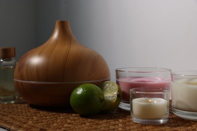 Photo of Spa composition with aroma oil diffuser and burning candles on table indoors, closeup