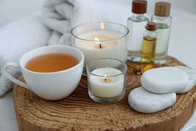 Photo of Spa composition with burning candles and cosmetic products on table, closeup