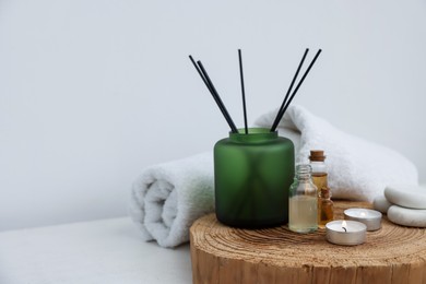 Photo of Spa composition with burning candles and reed air freshener on white table indoors. Space for text