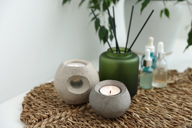 Photo of Spa composition with burning candles and reed air freshener on table indoors, closeup