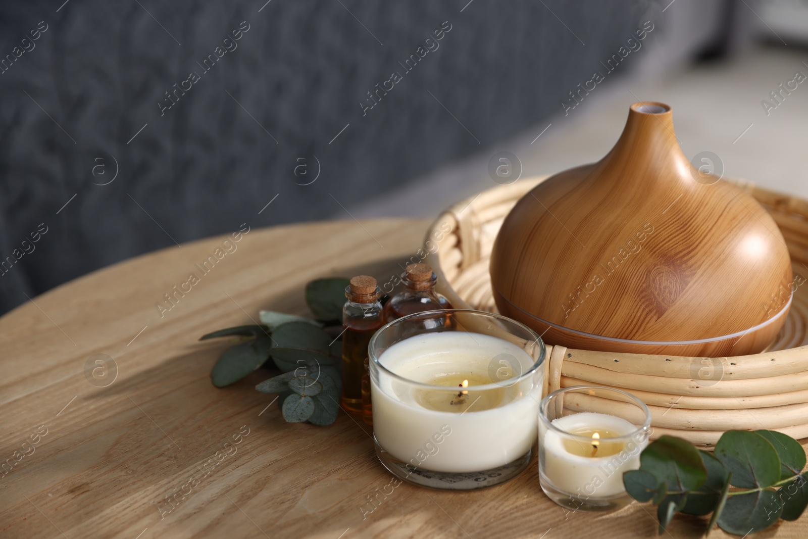 Spa composition with aroma oil diffuser and burning candles on wooden table indoors, closeup Photo of Spa composition with aroma oil diffuser and burning candles on wooden table indoors, closeup