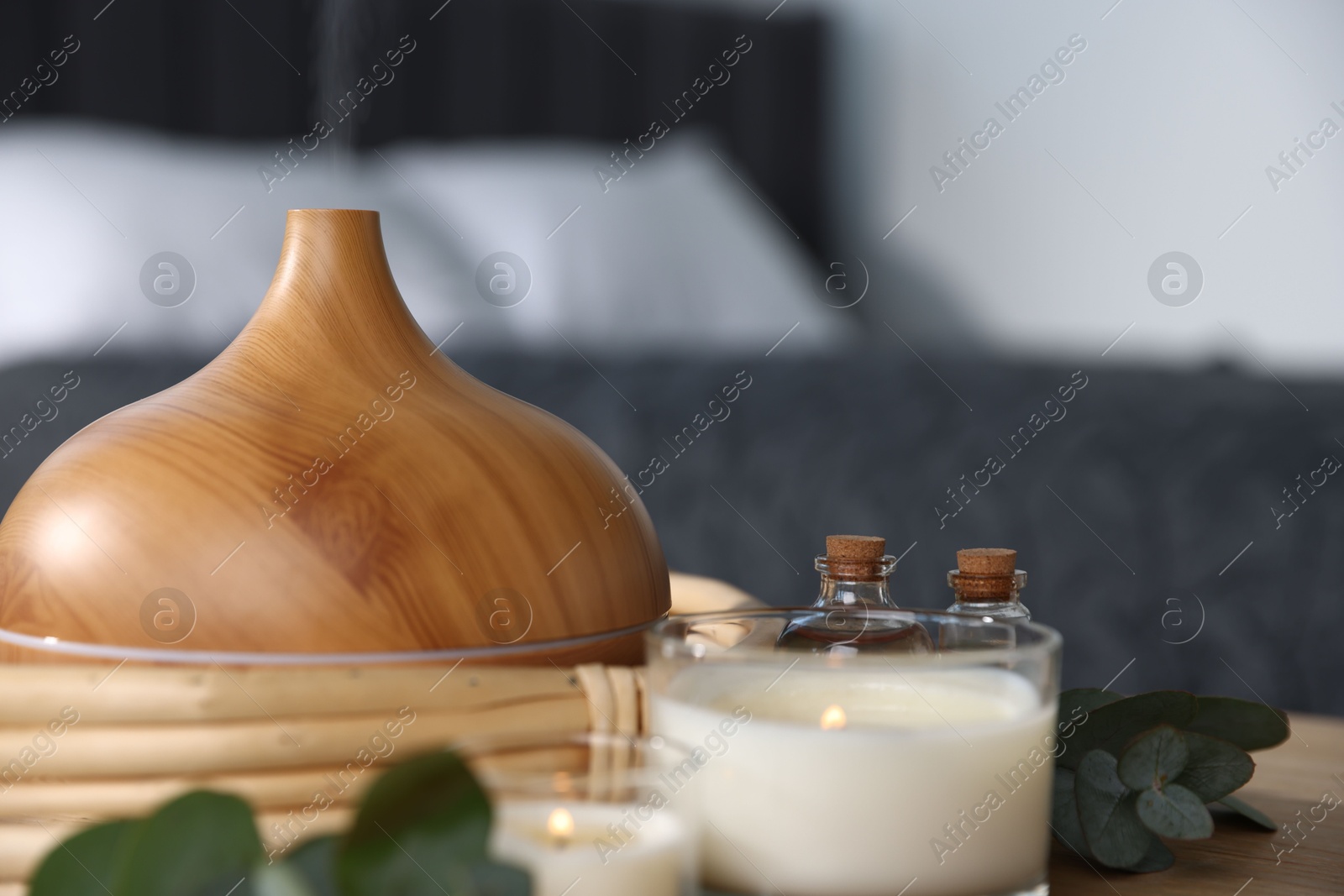 Spa composition with aroma oil diffuser and burning candles on table indoors, closeup Photo of Spa composition with aroma oil diffuser and burning candles on table indoors, closeup