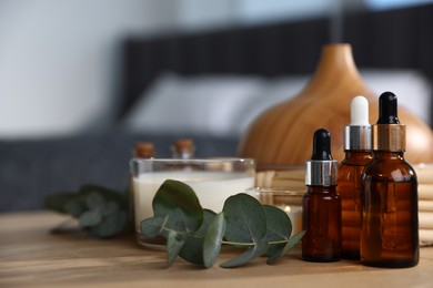 Photo of Spa composition with aroma oil diffuser and burning candles on wooden table, closeup