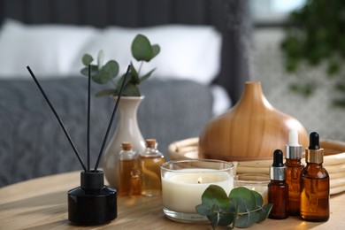 Photo of Spa composition with aroma oil diffuser, reed air freshener and burning candles on wooden table indoors