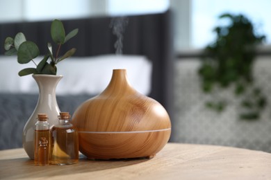 Photo of Spa composition with aroma oil diffuser and cosmetic products on wooden table indoors