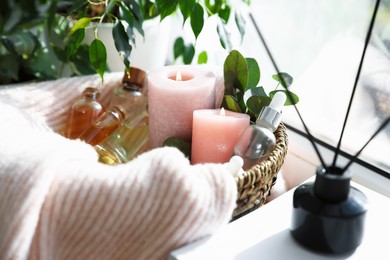 Photo of Spa composition. Burning candles, cosmetic products and reed air freshener on table indoors, closeup