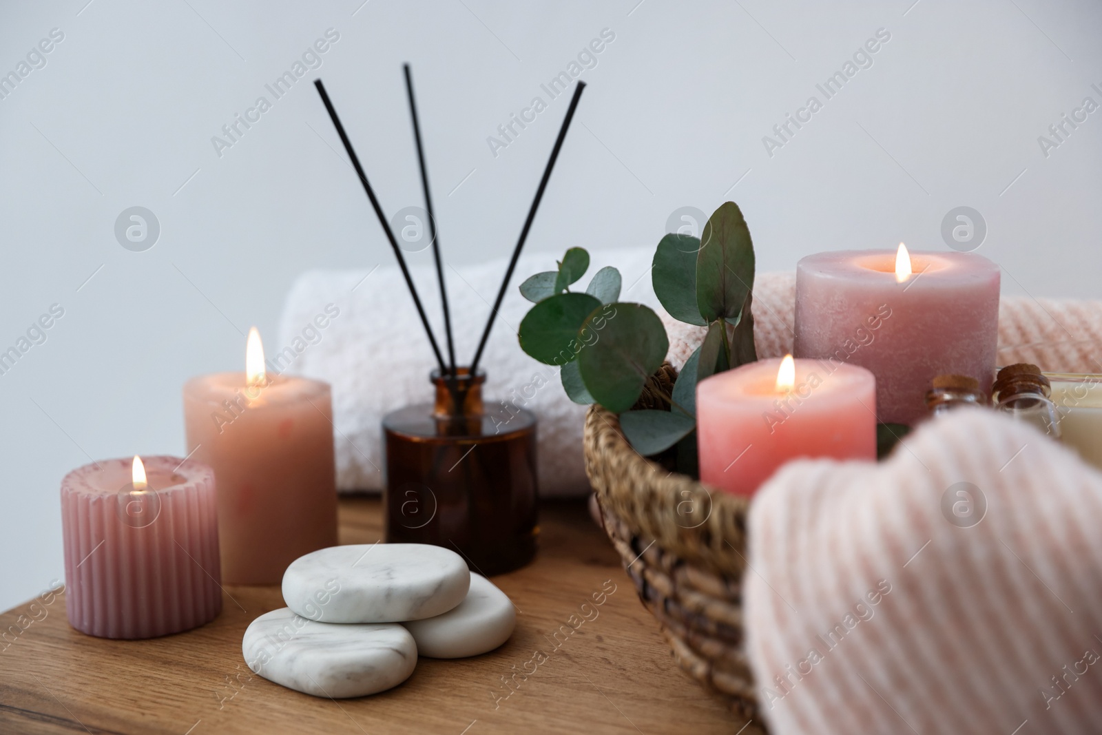 Spa composition with burning candles and reed air freshener on wooden table indoors, closeup Photo of Spa composition with burning candles and reed air freshener on wooden table indoors, closeup