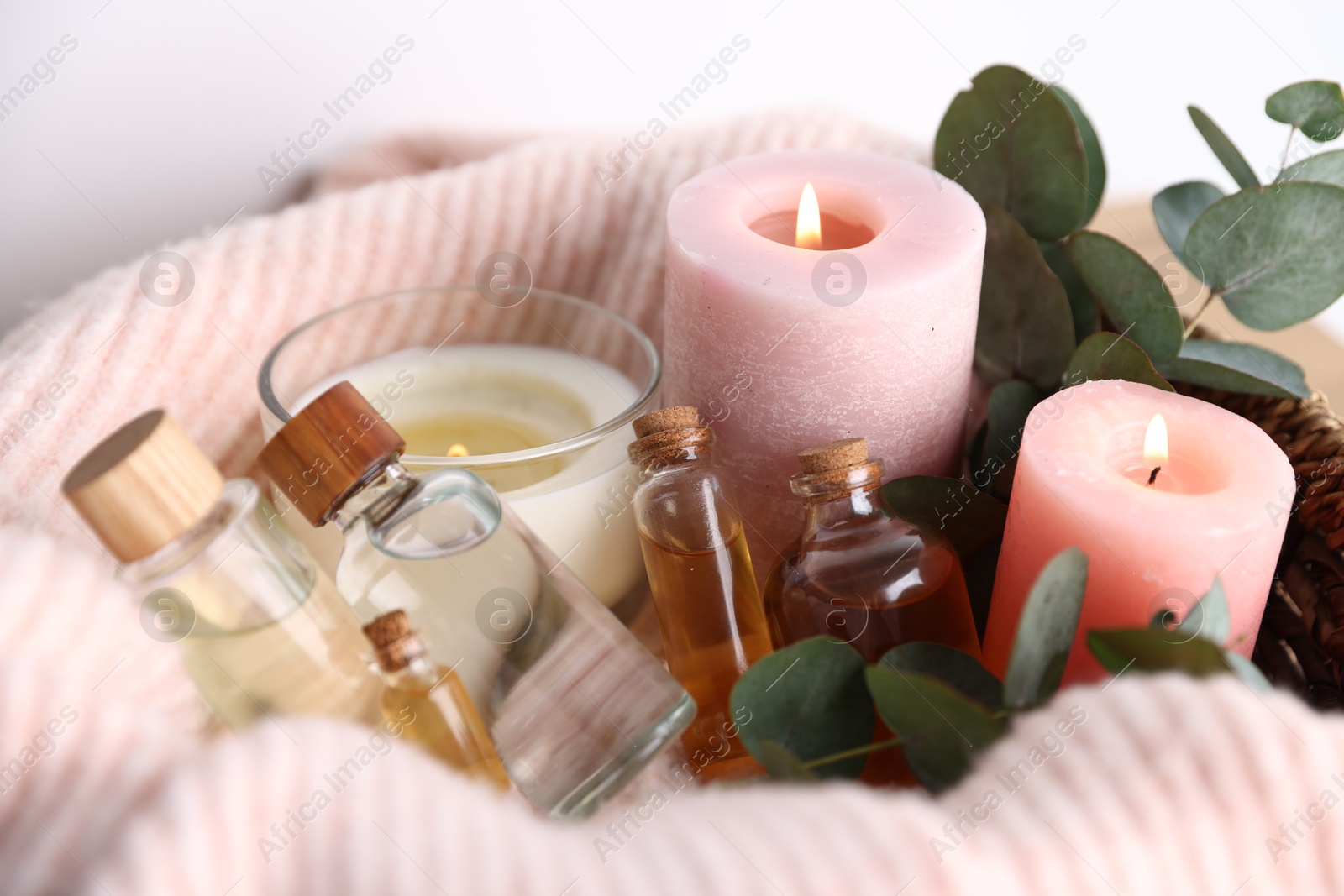 Photo of Spa composition. Burning candles, cosmetic products and eucalyptus branches on table, closeup