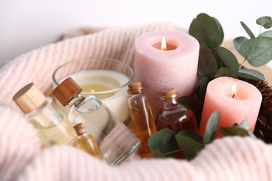 Photo of Spa composition. Burning candles, cosmetic products and eucalyptus branches on table, closeup