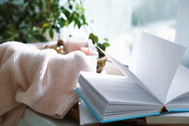 Photo of Spa composition. Burning candles and cosmetic products in basket with blanket indoors, focus on books