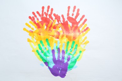 Photo of Tolerance concept. Heart of colorful handprints on white background, top view
