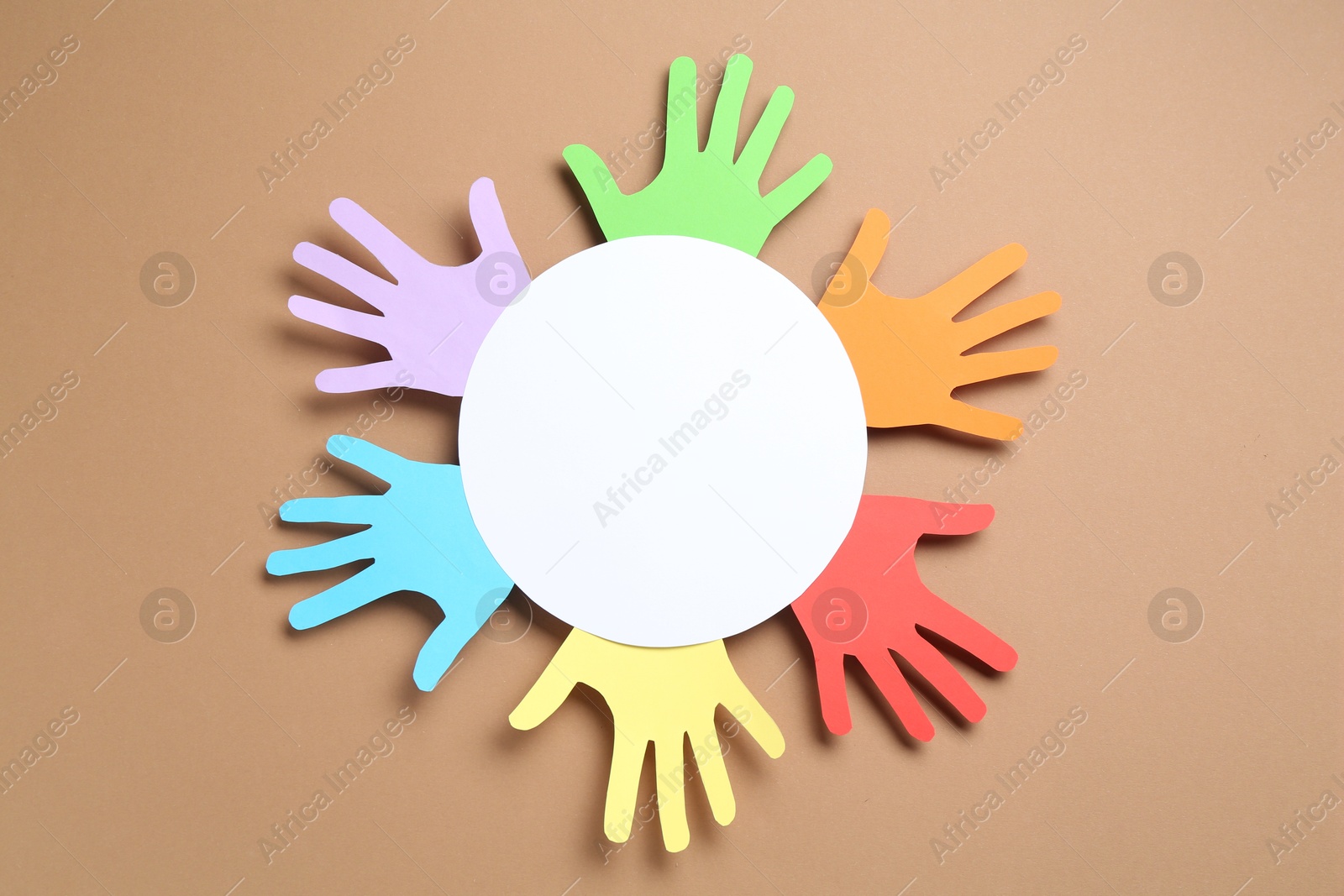 Tolerance concept. Colorful paper hands and empty card on brown background, top view. Space for text Photo of Tolerance concept. Colorful paper hands and empty card on brown background, top view. Space for text
