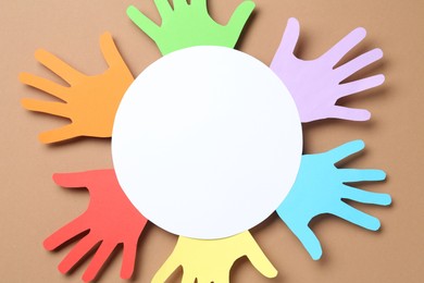 Photo of Tolerance concept. Colorful paper hands and empty card on brown background, top view. Space for text