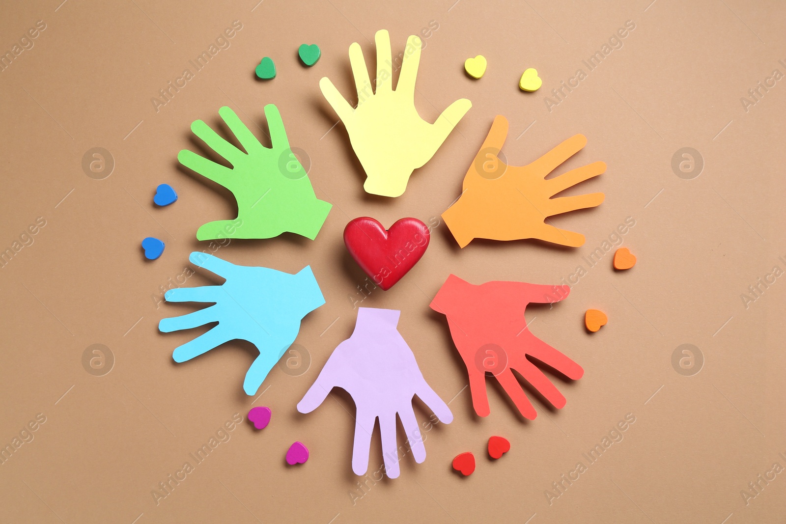 Tolerance concept. Colorful paper hands and hearts on brown background, flat lay Photo of Tolerance concept. Colorful paper hands and hearts on brown background, flat lay