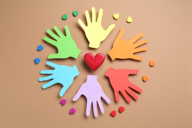 Photo of Tolerance concept. Colorful paper hands and hearts on brown background, flat lay