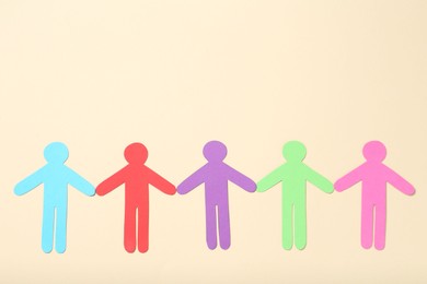 Photo of Tolerance concept. Colorful human figures on beige background, flat lay. Space for text