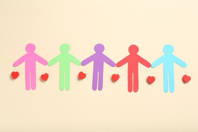 Photo of Tolerance concept. Colorful human figures and hearts on beige background, flat lay