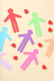 Photo of Tolerance concept. Colorful human figures and hearts on beige background, flat lay