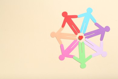 Photo of Tolerance concept. Colorful human figures and heart on beige background, flat lay. Space for text