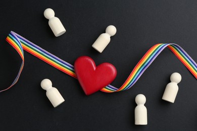 Photo of Tolerance concept. Human figures, heart and colorful ribbon on black background, flat lay