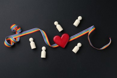 Photo of Tolerance concept. Human figures, heart and colorful ribbon on black background, flat lay