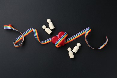 Photo of Tolerance concept. Human figures, heart and colorful ribbon on black background, flat lay
