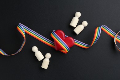 Photo of Tolerance concept. Human figures, heart and colorful ribbon on black background, flat lay