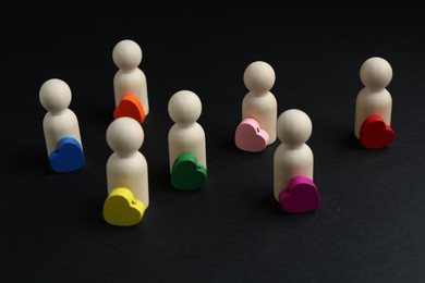 Photo of Tolerance concept. Human figures and colorful hearts on black background, closeup