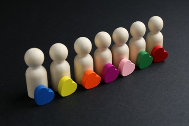 Photo of Tolerance concept. Human figures and colorful hearts on black background, closeup