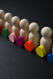 Photo of Tolerance concept. Human figures and colorful hearts on black background, closeup
