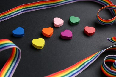 Photo of Tolerance concept. Colorful hearts and ribbon on black background, closeup