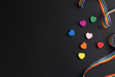 Photo of Tolerance concept. Colorful hearts and ribbon on black background, flat lay. Space for text
