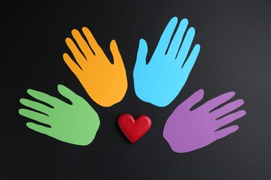 Photo of Tolerance concept. Colorful paper hands and heart on black background, flat lay