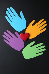 Photo of Tolerance concept. Colorful paper hands and heart on black background, flat lay