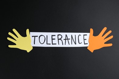 Photo of Card with word Tolerance and colorful paper hands on black background, flat lay