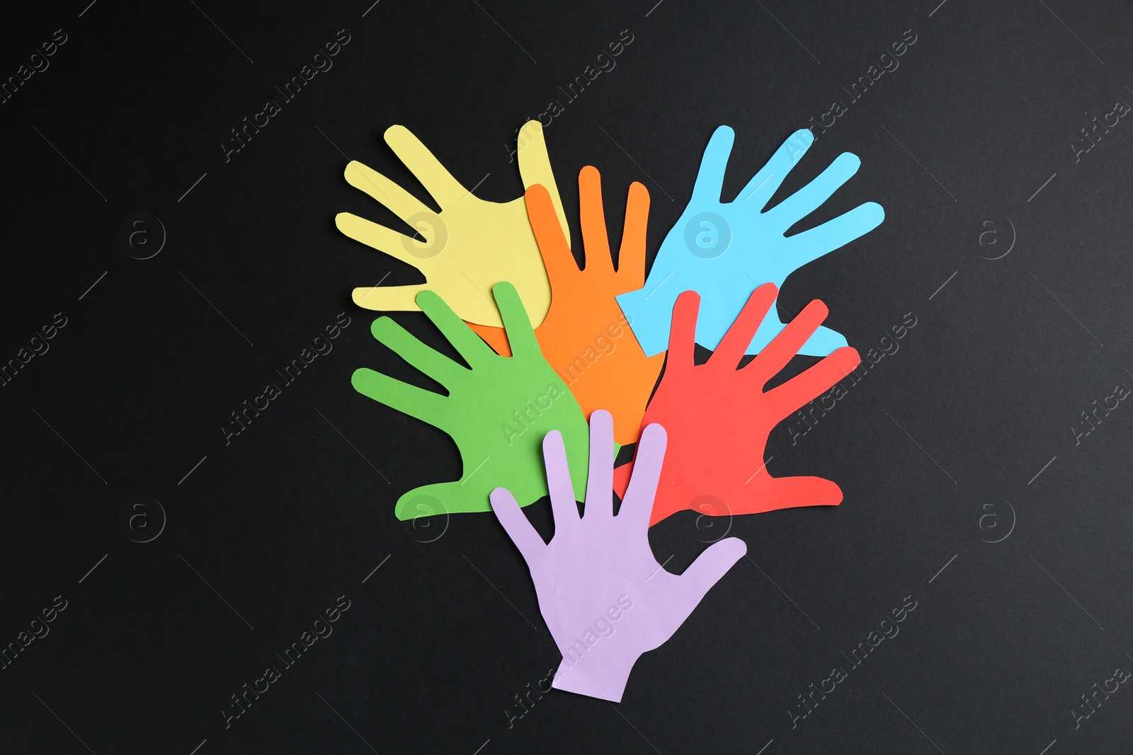 Tolerance concept. Colorful paper hands on black background, flat lay Photo of Tolerance concept. Colorful paper hands on black background, flat lay