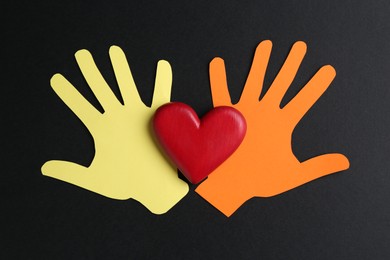 Photo of Tolerance concept. Colorful paper hands and heart on black background, flat lay